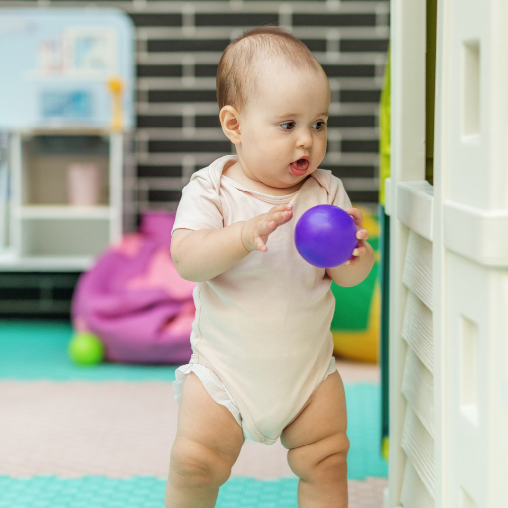 Bebé trabajando el desarrollo motor a través de la psicomotricidad gruesa, jugando con pelotas.